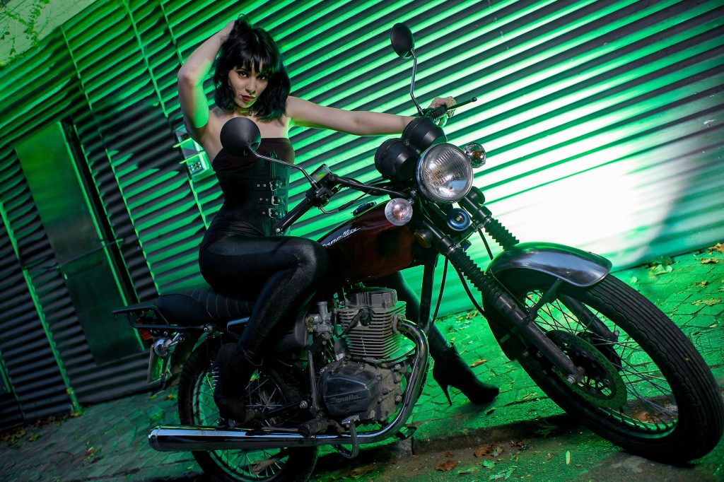 Retrato de Carmin chica motociclista con su moto usando el en ultra angular. Iluminación strobist, softbox, mas rebote suave y fondo iluminado con flash verse sobre metal corrugado