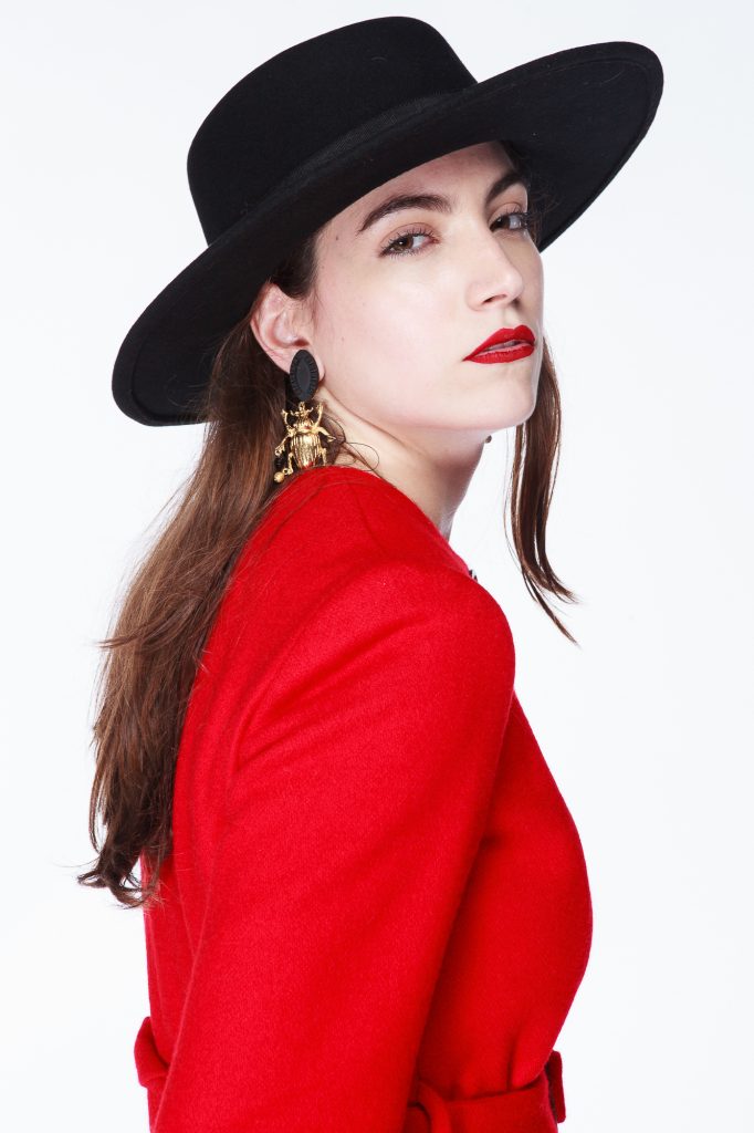 Foto de modelo con sobrero negro y tapado rojo en clave alta.