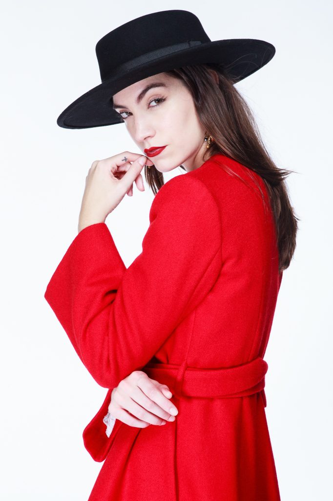 Foto de modelo con sobrero negro y tapado rojo en clave alta.
