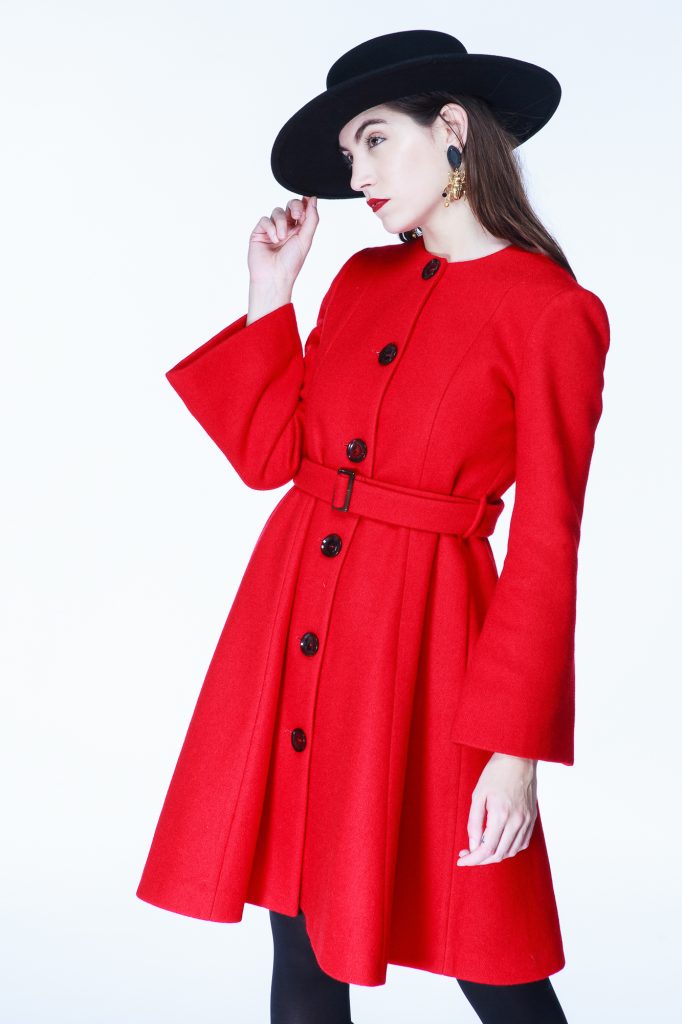 Foto de modelo con sobrero negro y tapado rojo en clave alta.