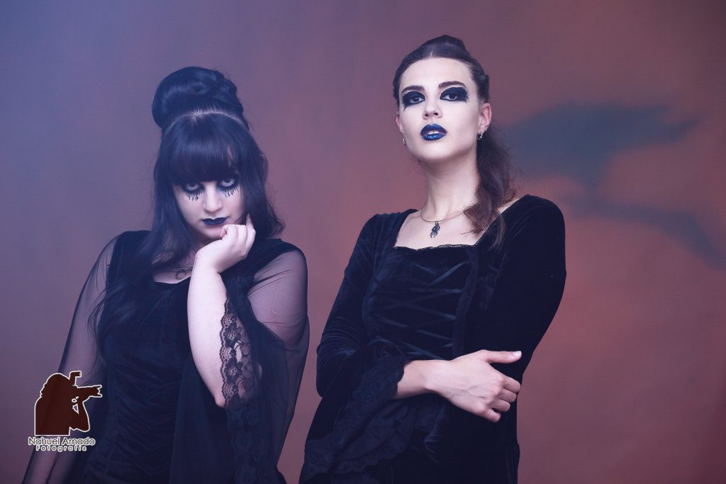 Foto editorial con vestidos de altwa costura, maquillaje artístico de liz-trent. Outfit gótico, iluminación de estudio, luces rojizas en fondo con sobra de cuervo proyectada.  