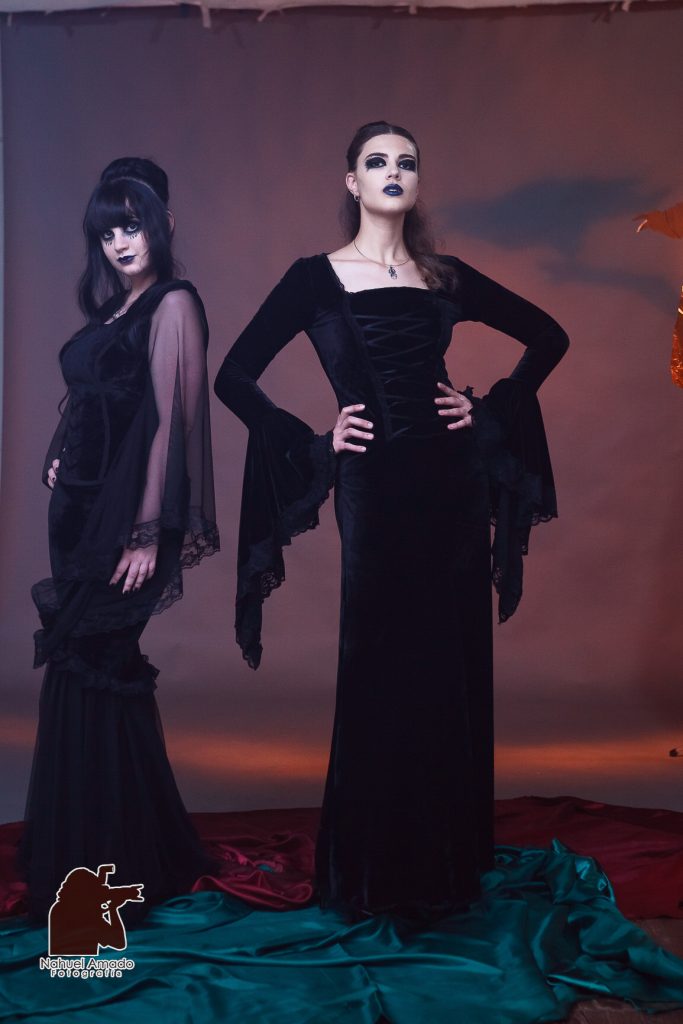 Foto editorial con vestidos de altwa costura, maquillaje artístico de liz-trent. Outfit gótico, iluminación de estudio, luces rojizas en fondo con sobra de cuervo proyectada.  