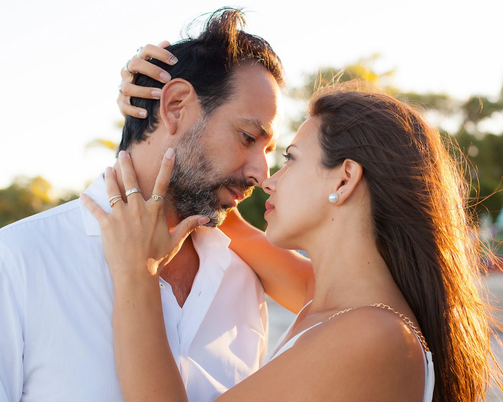 Foto de pareja mirándose apasionadamente en atardecer, primer plano, ella sostiene apasionadamente el cuello y cabeza de su pareja.