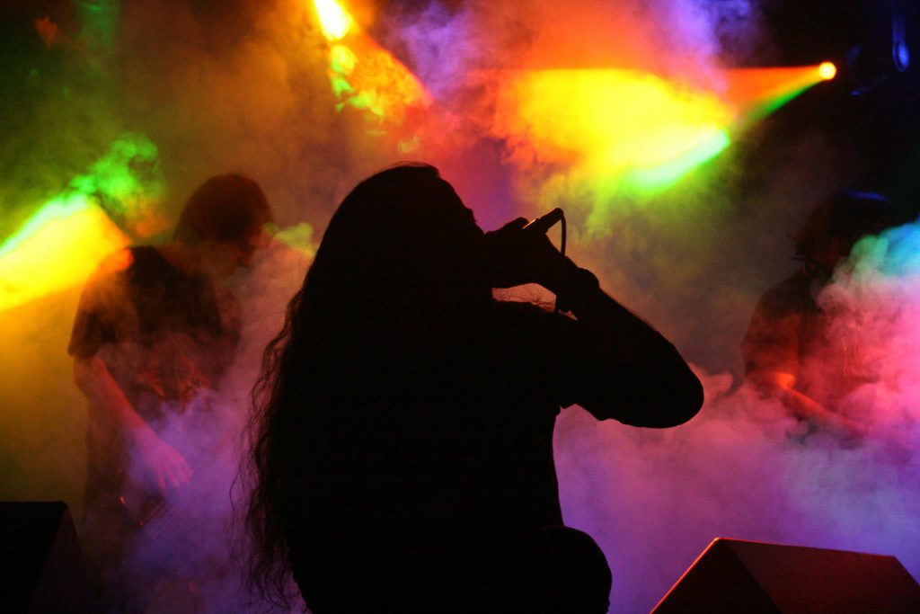 Cantante de Sacificio bizarro tocando en vivo en silueta con luces sobre humo de fondo